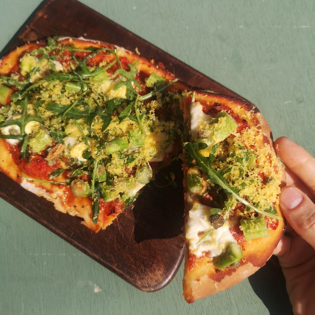 Tosta con palta y espárragos sobre tabla de madera